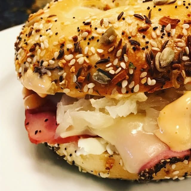 Everything bagel sandwich with hot deli meat, sauerkraut, cheese, and sauce