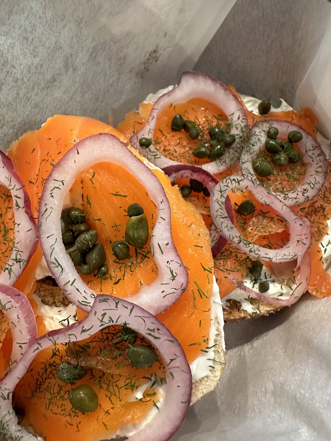 Open-faced lox bagel with red onion, capers, and dill